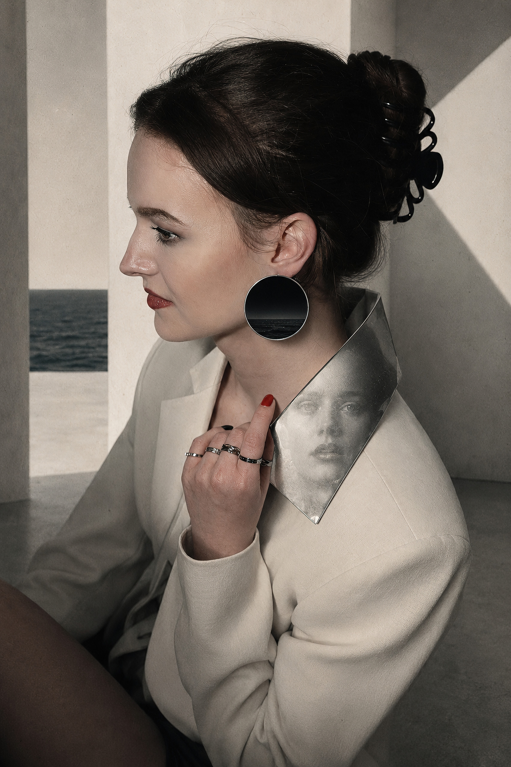 Profile of a woman in a cream coat, a black disc at her ear and a face surfacing in the polished metal at her shoulder — collage by Hamudi Leon